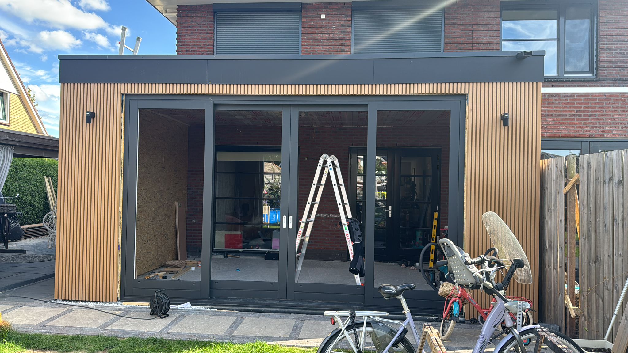 Vooraanzicht uitbouw met schuifpui en houten gevelbekleding